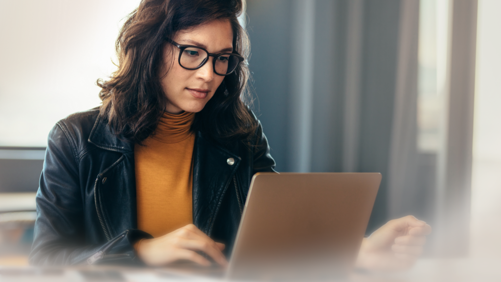 Woman with glasses and dark hair sitting in front of computer.