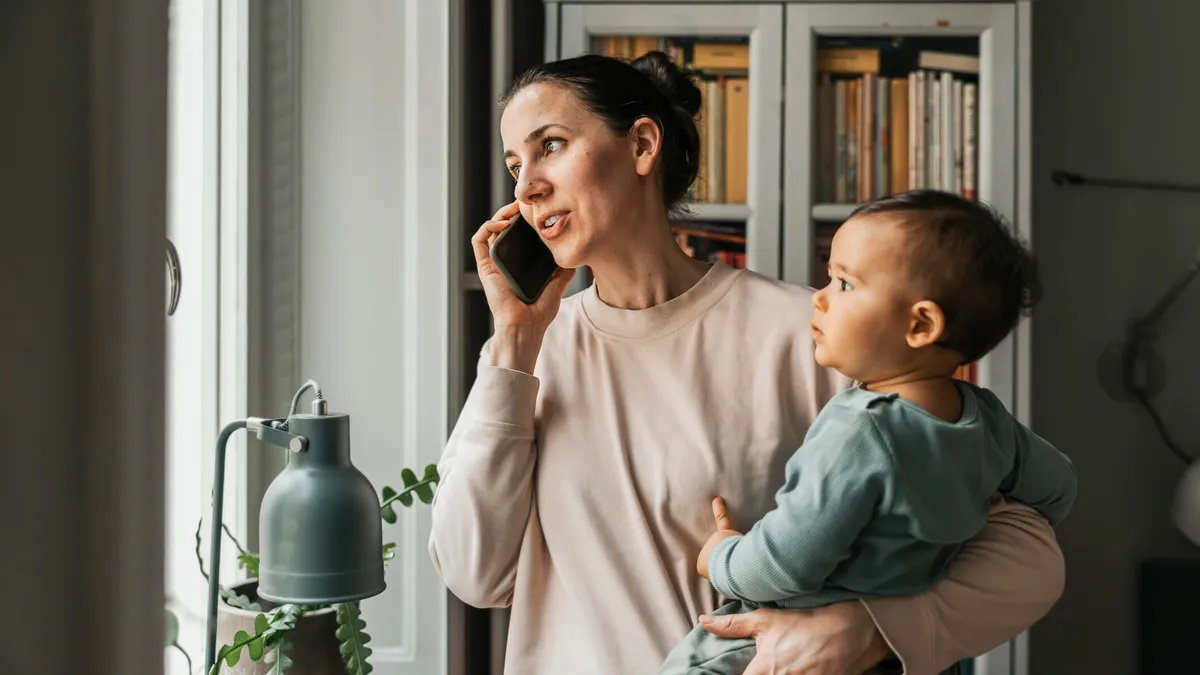 A woman holding a baby while on the phone.